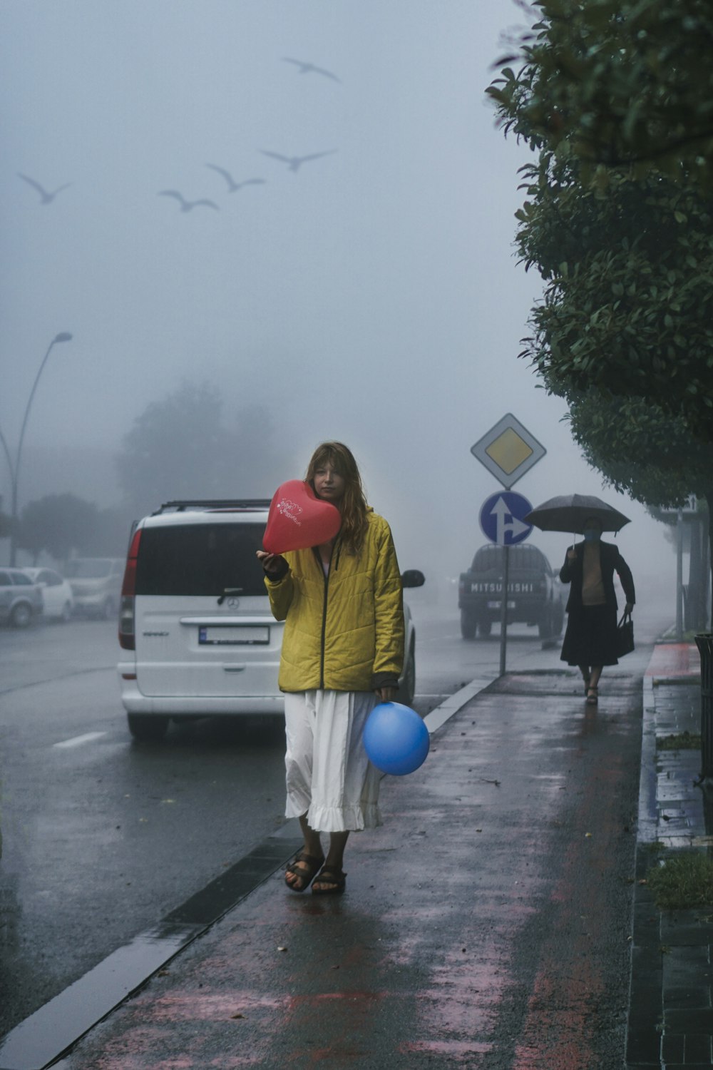 woman in yellow jacket holding blue balloon