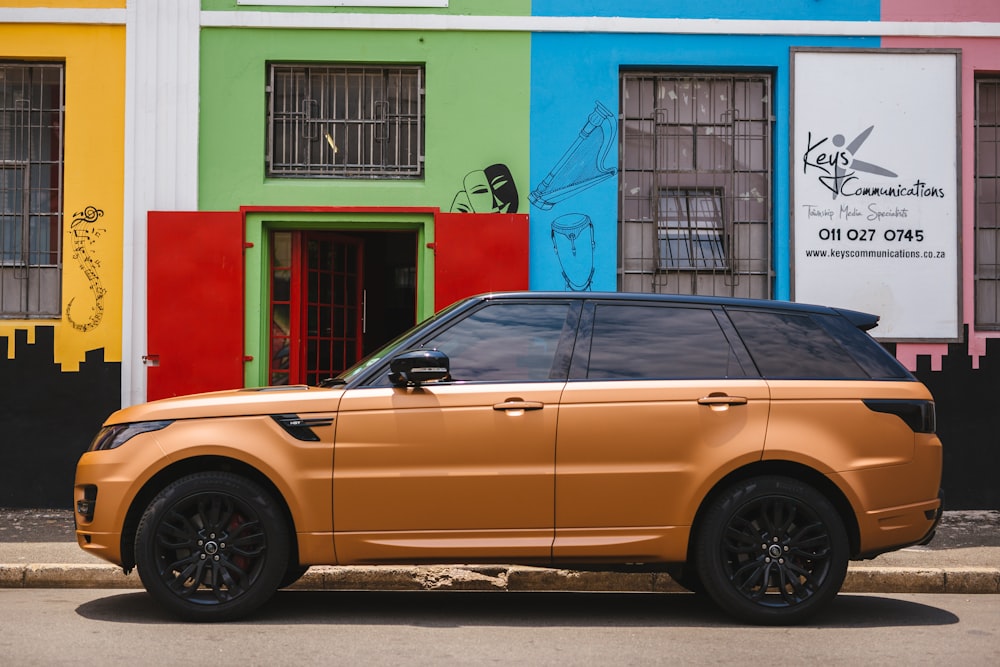 brown suv parked beside green and pink concrete building during daytime