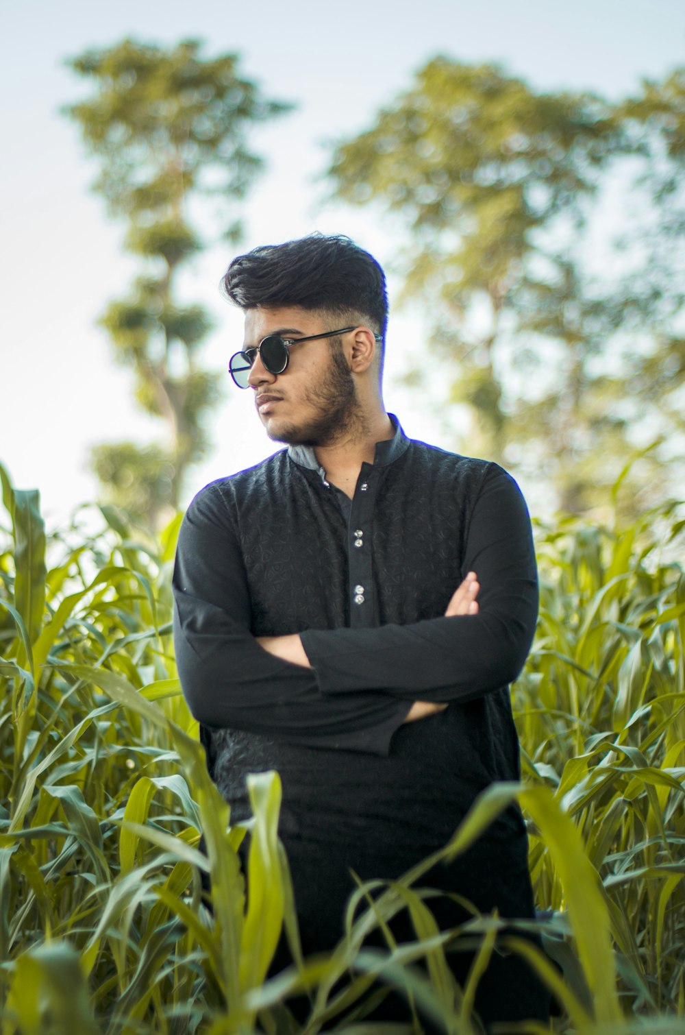 man in black button up long sleeve shirt and black sunglasses sitting on green grass during