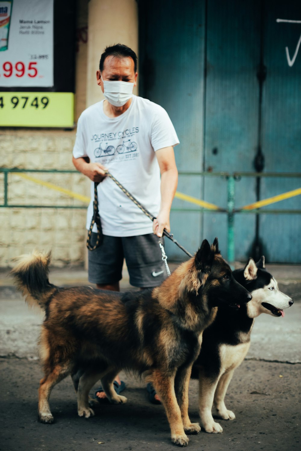 man in white t-shirt and blue denim jeans standing beside black and white siberian