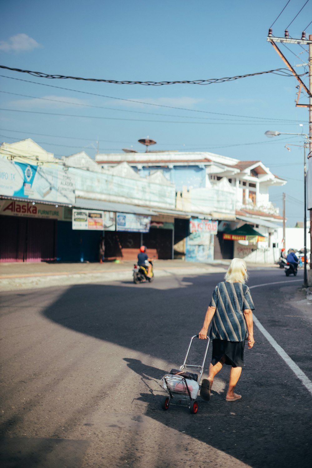 hombre con camisa blanca y pantalones cortos negros caminando por la calle durante el día
