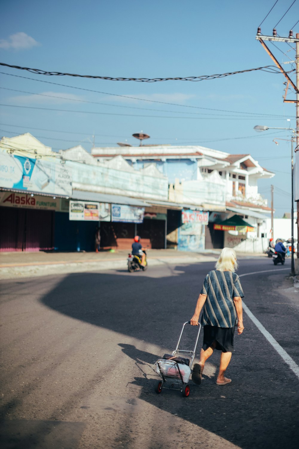 man in white shirt and black shorts walking on street during daytime