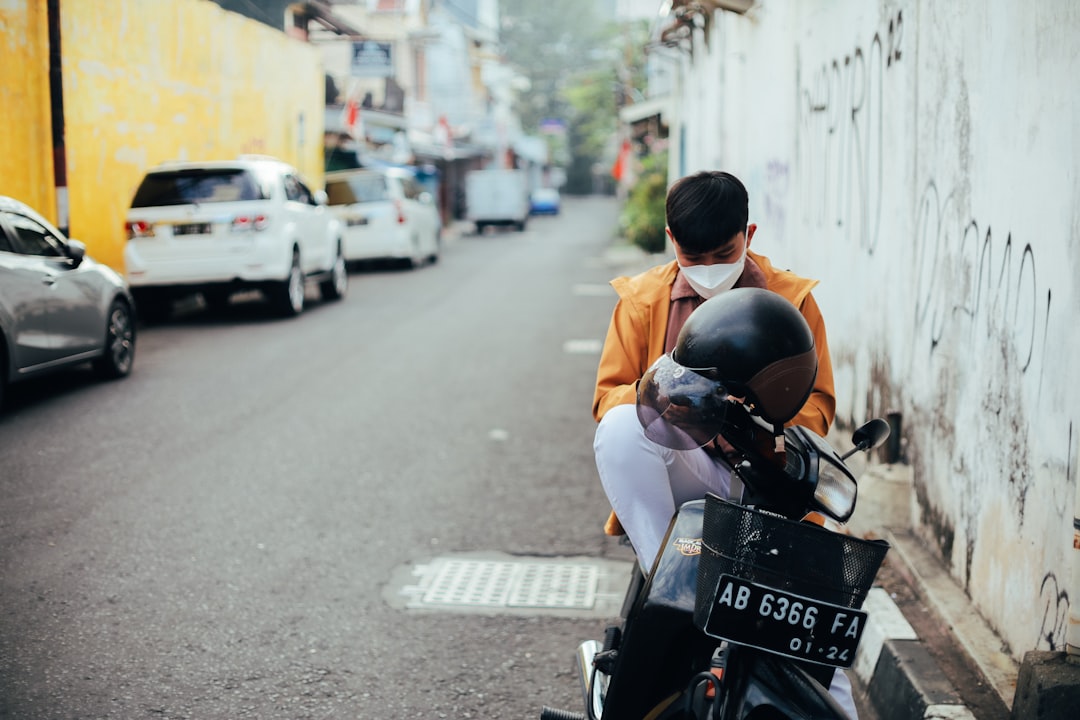 man in white dress shirt riding motorcycle on road during daytime