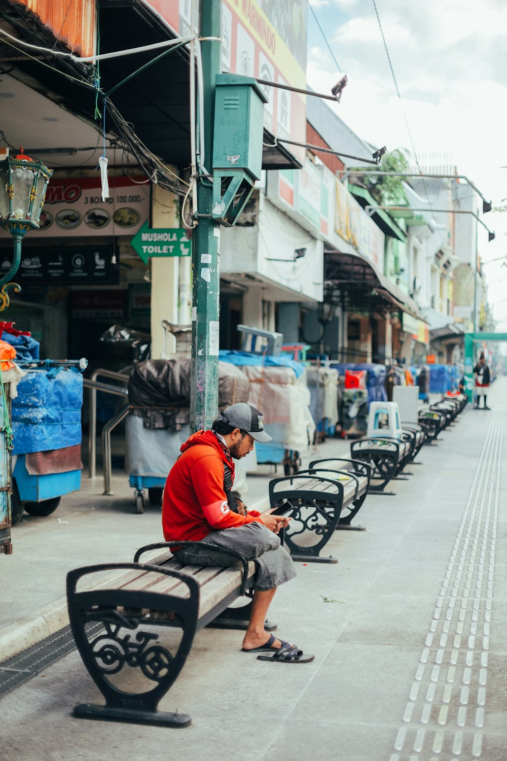 a man sitting on a bench next to a row of benches