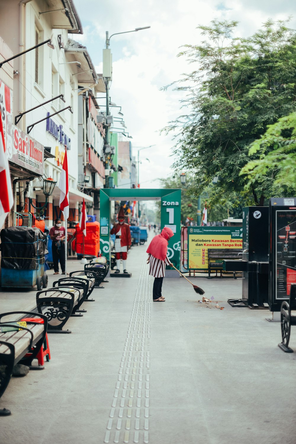 woman in red and white stripe long sleeve shirt walking on sidewalk during daytime