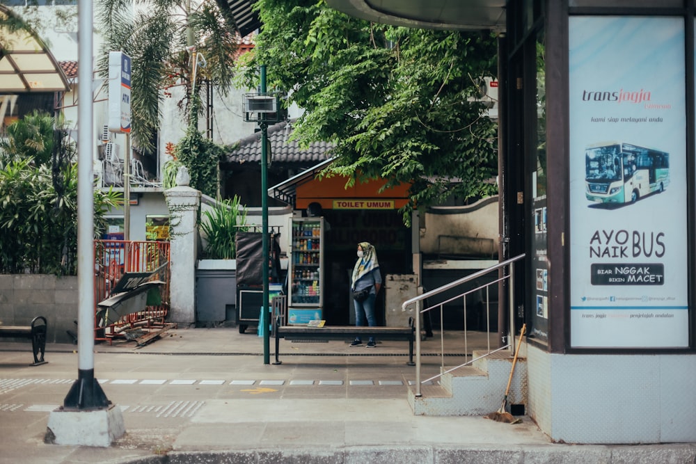 woman in black coat standing near black metal gate during daytime