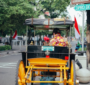 2 children riding on yellow and black auto rickshaw on road during daytime