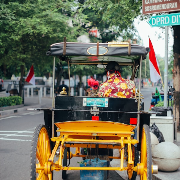 2 children riding on yellow and black auto rickshaw on road during daytime