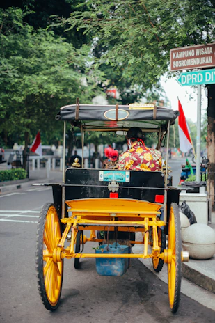 2 children riding on yellow and black auto rickshaw on road during daytime