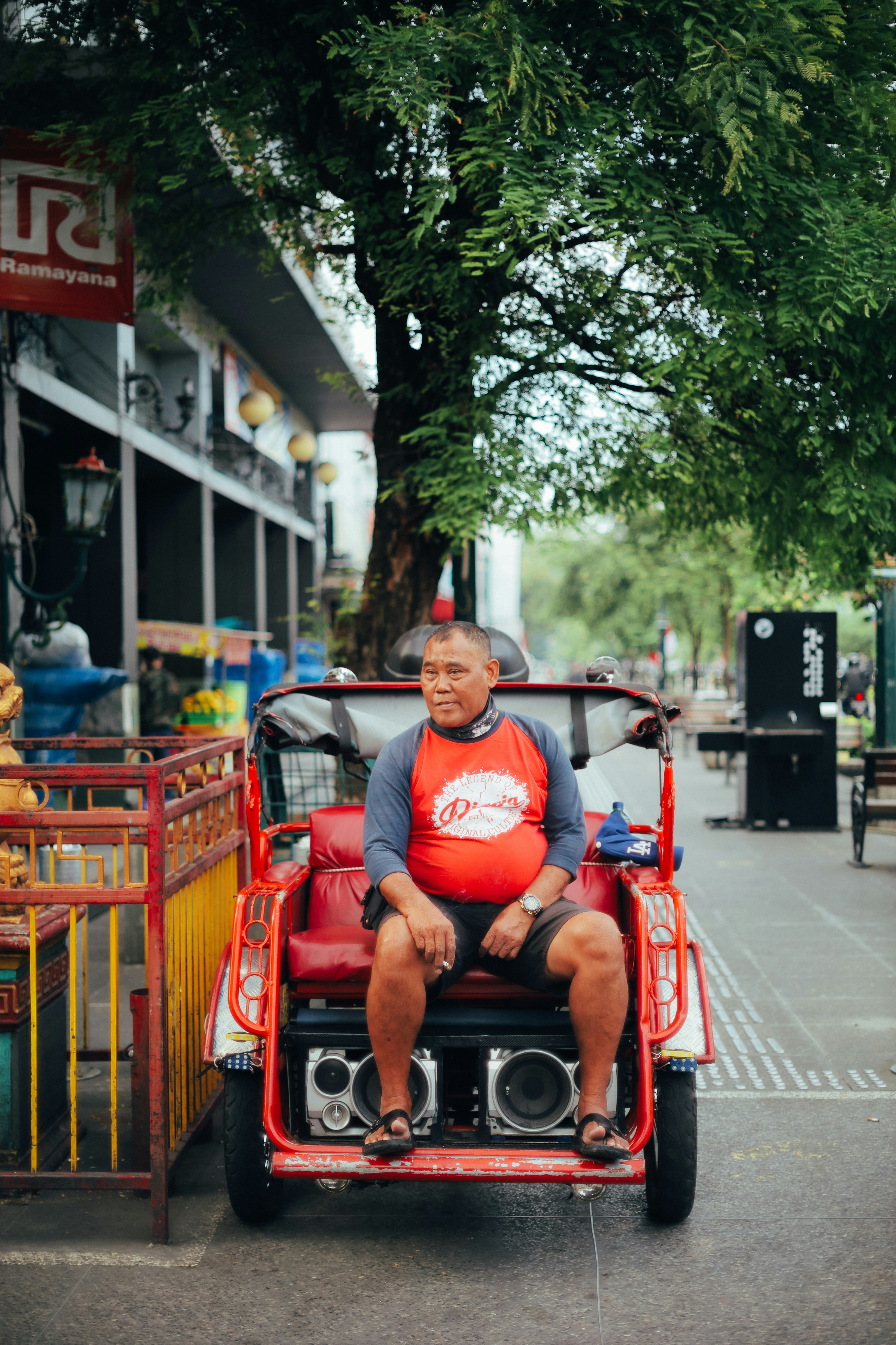 man in red crew neck t-shirt sitting on red wooden bench during daytime