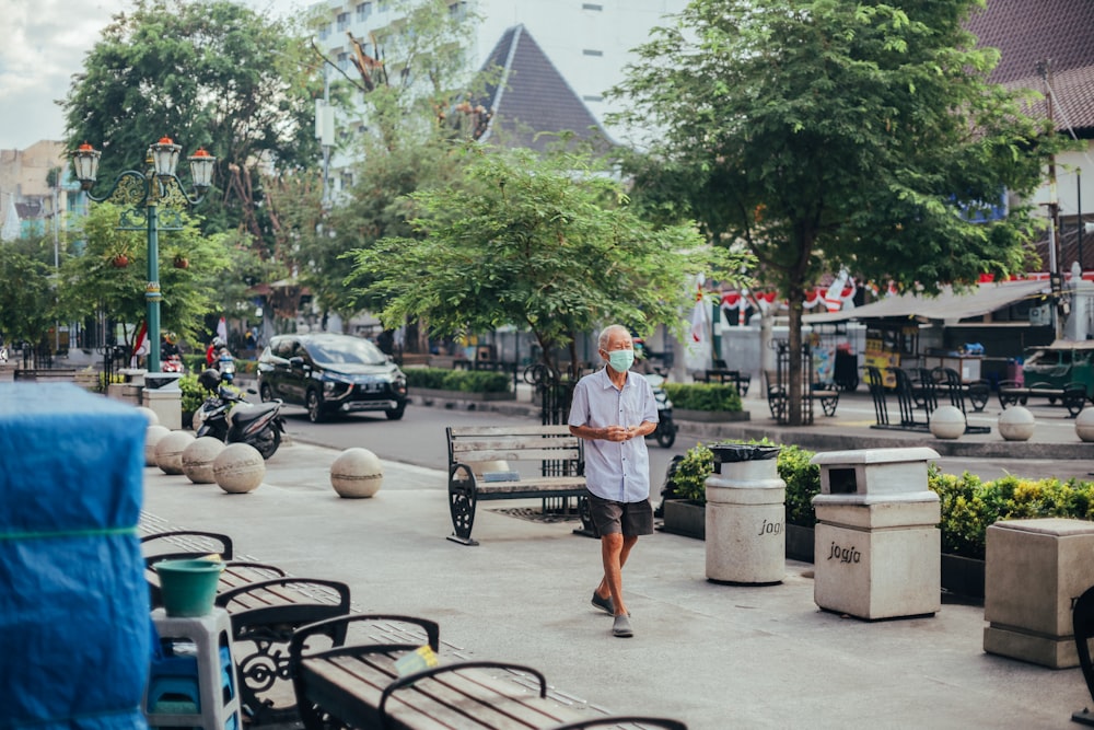 man in white t-shirt and blue shorts standing near black metal table and chairs