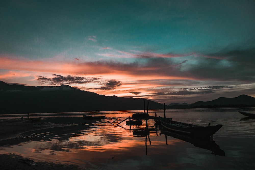 silhouette of boat on water during sunset