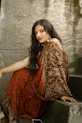 woman in red and gold sari dress sitting on gray concrete stairs