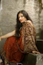 woman in red and gold sari dress sitting on gray concrete stairs