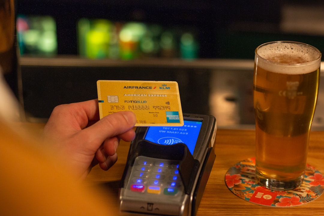 person holding yellow and blue card, Paying with American Express for a Beer