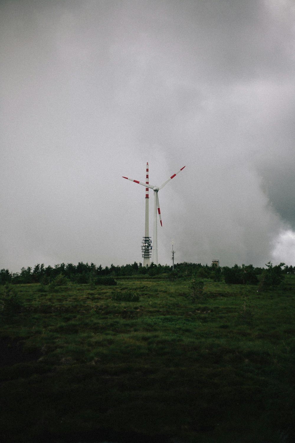 white and red windmill on green grass field under white clouds during daytime