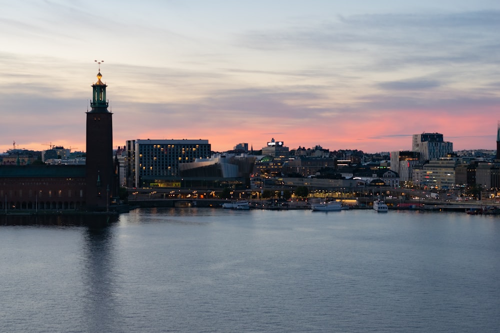 body of water near city buildings during sunset