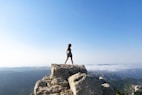 woman in black tank top standing on rock formation during daytime