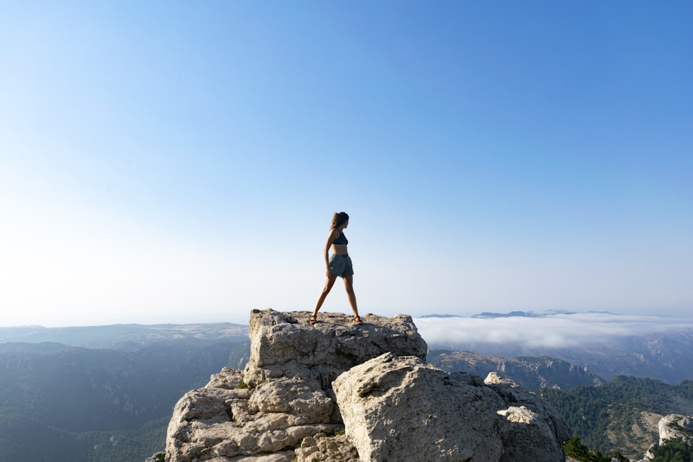 woman in black tank top standing on rock formation during daytime