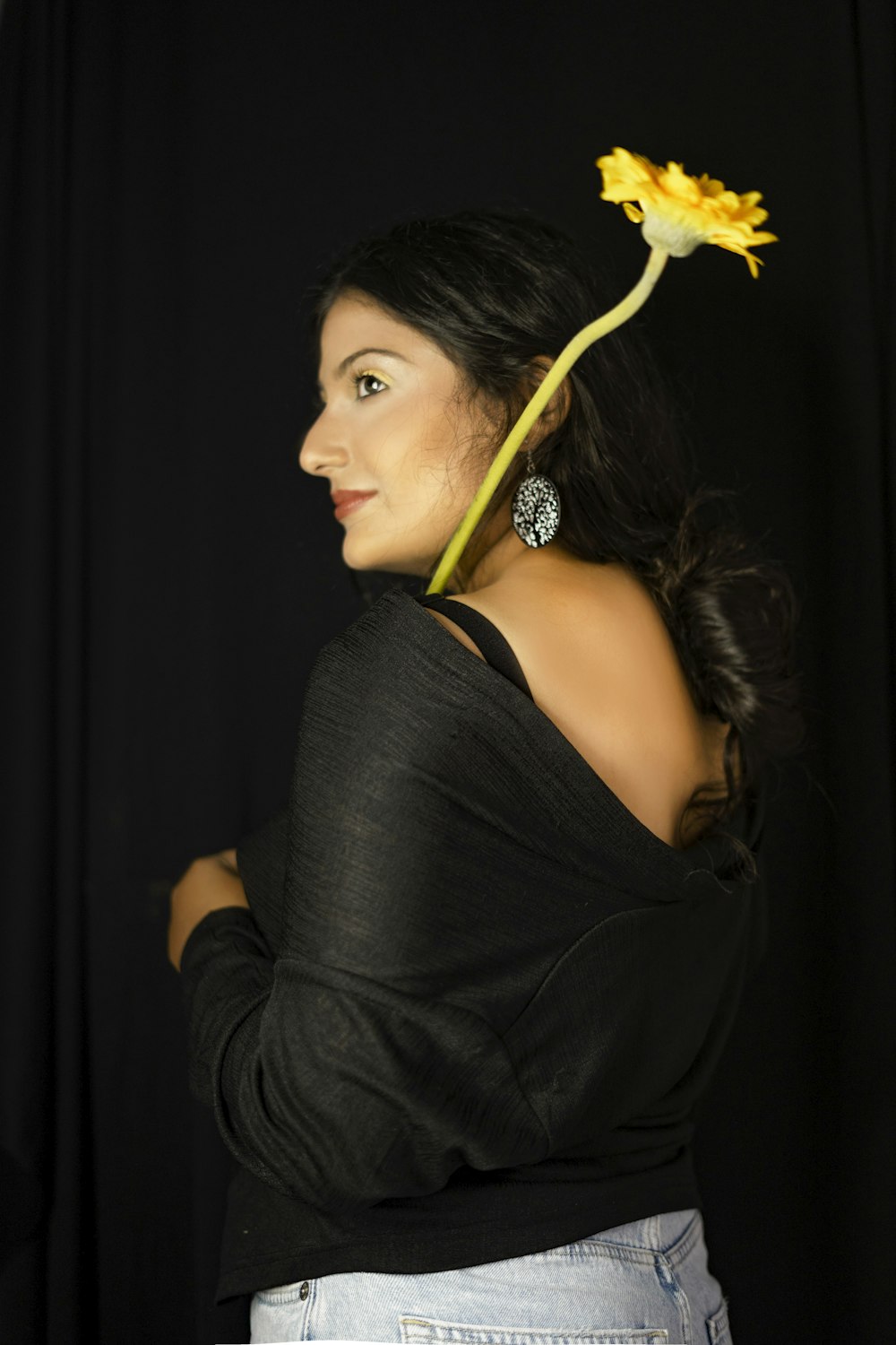 woman in black tank top holding yellow flower