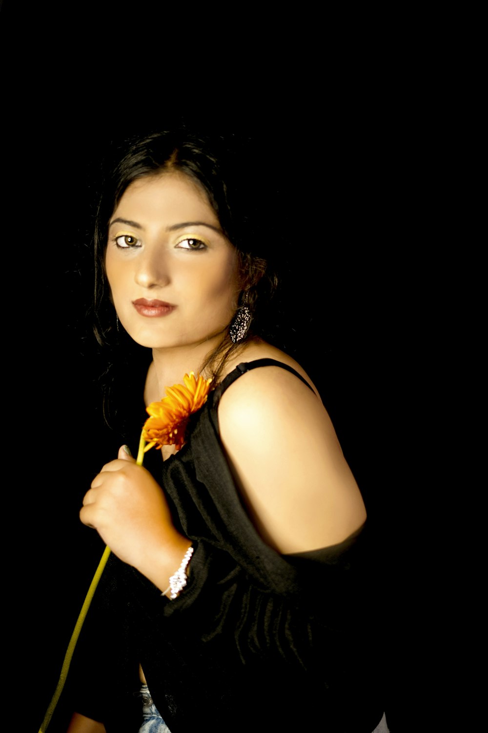 woman in black sleeveless top holding yellow flower