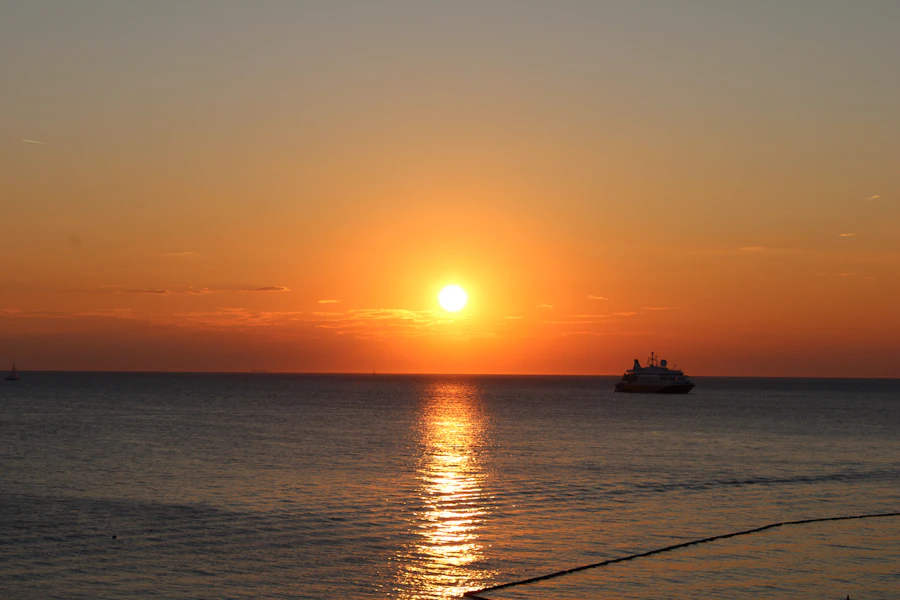 silhouette of boat on sea during sunset