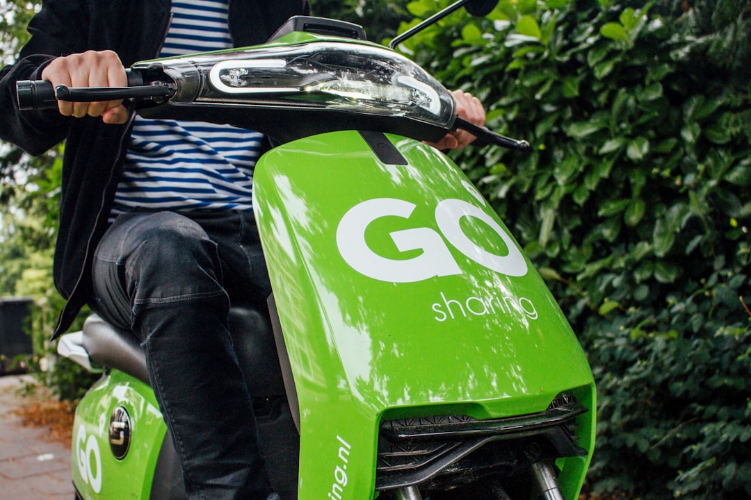 person in blue denim jeans sitting on green motorcycle