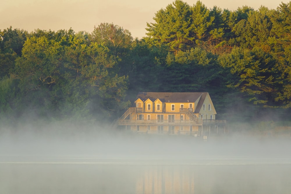 brown wooden house near green trees and lake during daytime