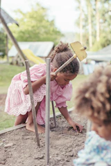 girl in pink dress sitting on brown wooden chair