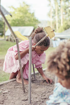 girl in pink dress sitting on brown wooden chair