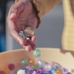 person holding pink yellow and silver beads