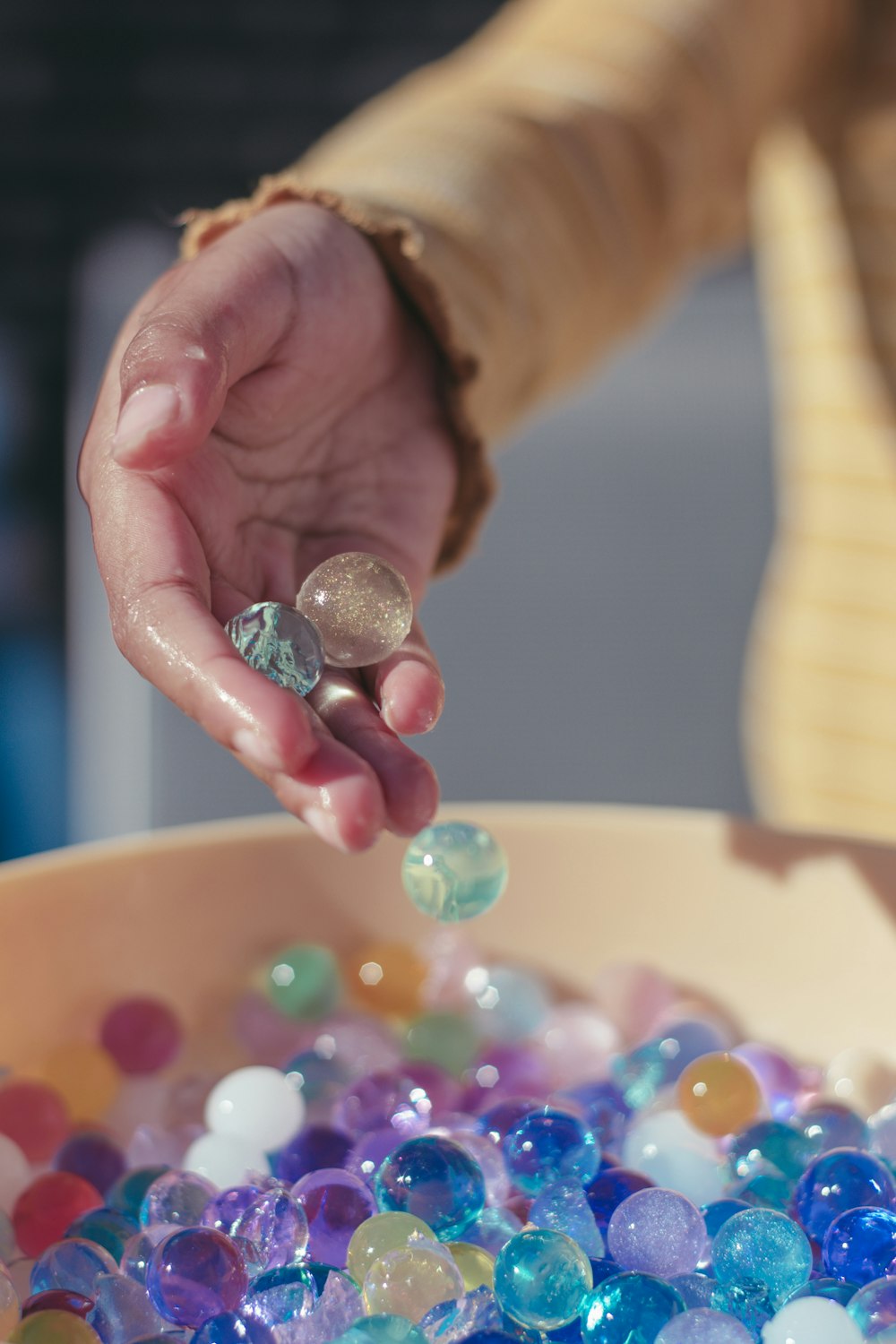 person holding pink yellow and silver beads