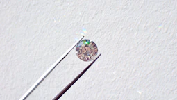 Close-up of a jeweler's hands inspecting a sparkling diamond with a magnifying loupe under bright light.