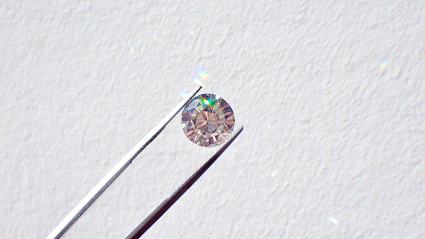 A sparkling light blue diamond resting on a soft white silk cloth under gentle lighting.