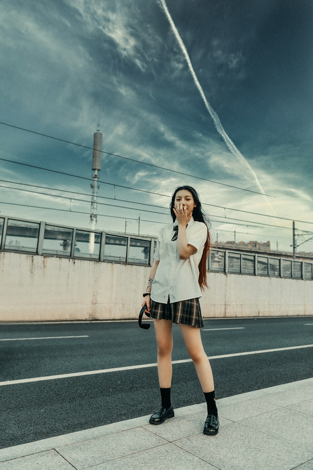 woman in white shirt and black skirt standing on road during daytime