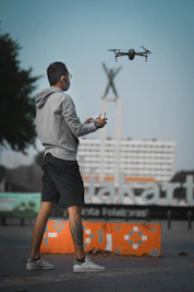 a man in a hoodie is flying a remote controlled airplane