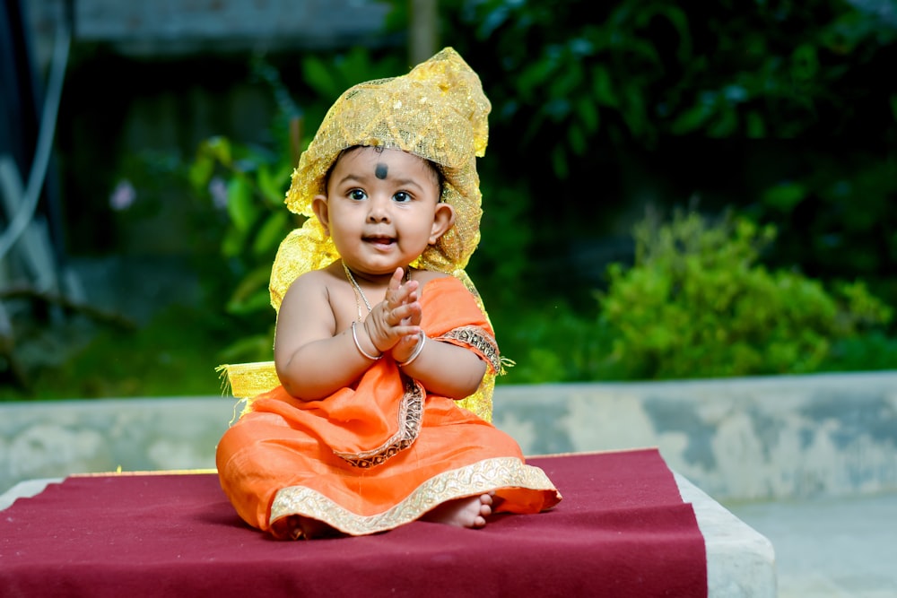 girl in yellow dress sitting on red textile