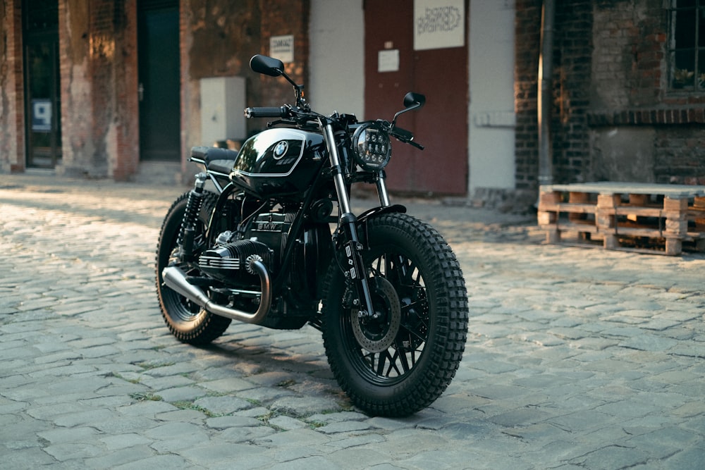 black cruiser motorcycle parked beside brown concrete building during daytime