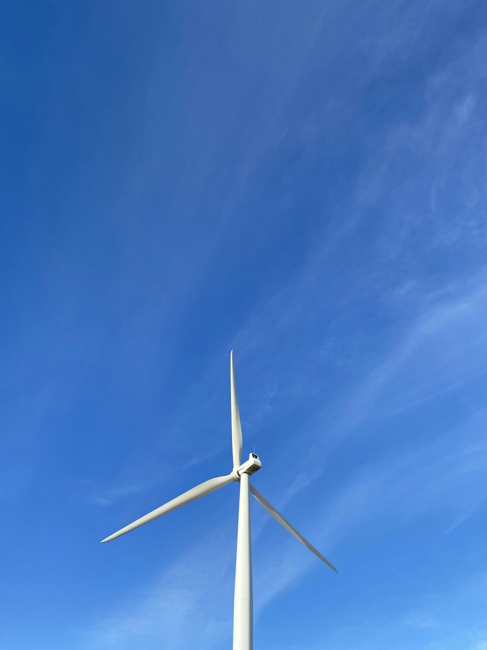 white wind turbine under blue sky during daytime