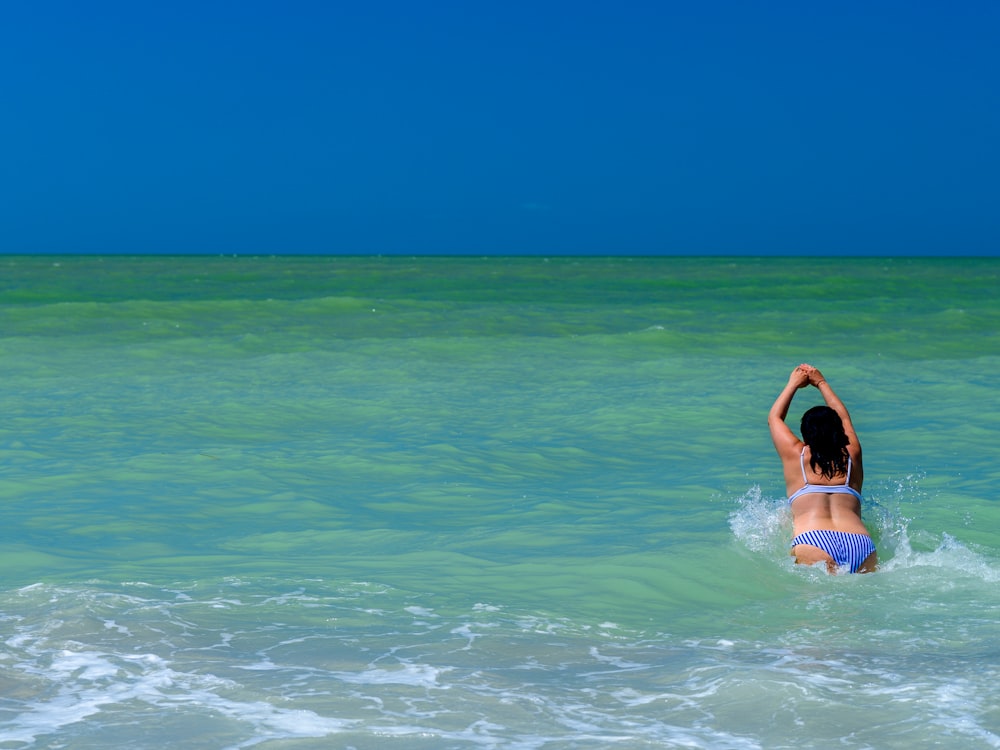 woman in blue and white bikini top on water during daytime