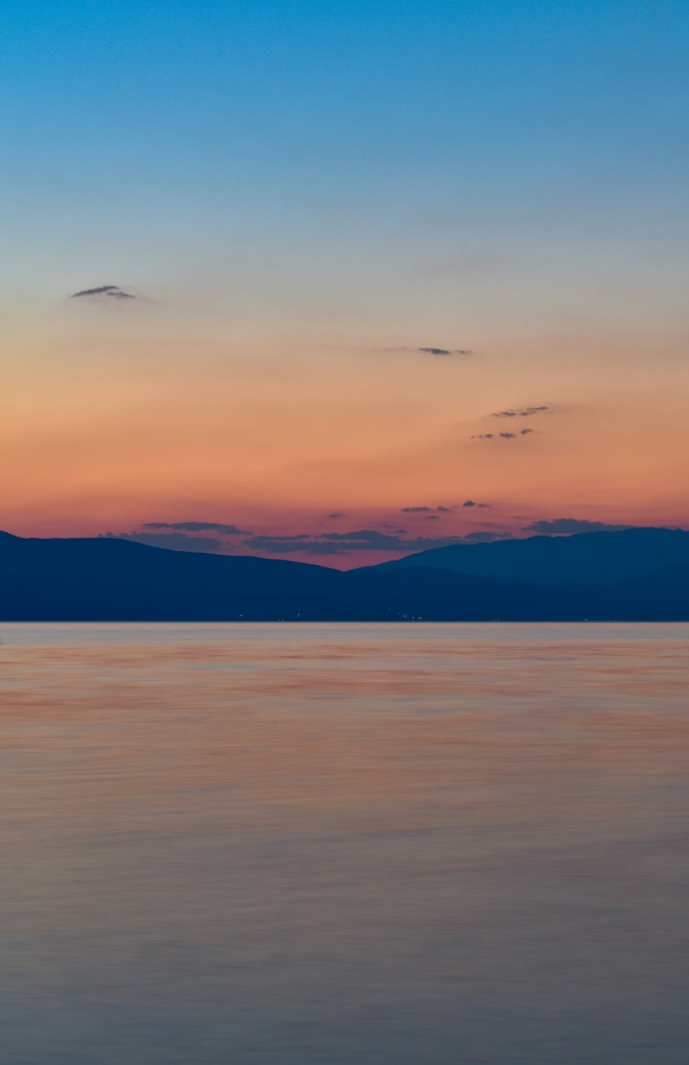 body of water near mountain during sunset