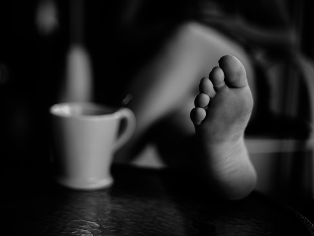 grayscale photo of person holding mug