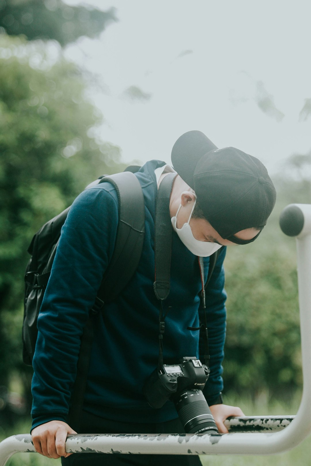 man in blue jacket and gray cap holding black dslr camera