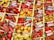 A vibrant assortment of various pepper varieties displayed in wooden crates. Each type of pepper is labeled with a card indicating its name and origin. The peppers range in color from bright red and yellow to orange and green, showcasing a diverse selection of shapes and sizes.