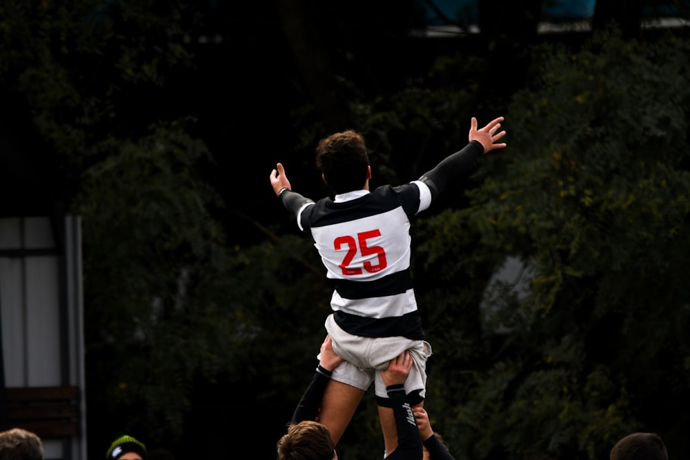 man in black and white jersey shirt and black pants running on field during daytime