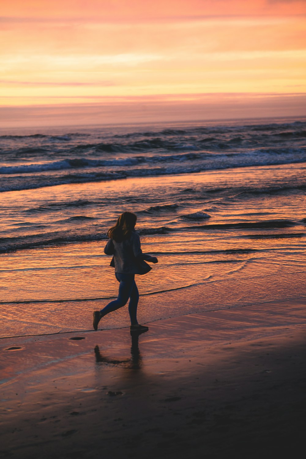 일몰 동안 해변을 걷는 여자