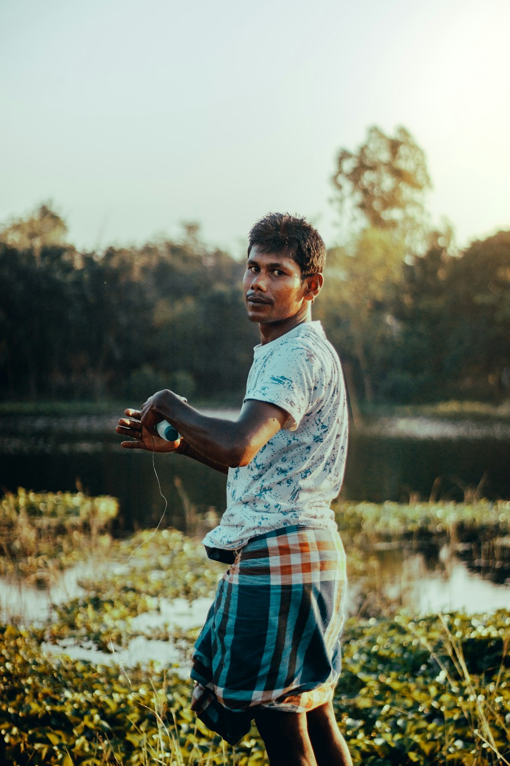 man in white t-shirt and red and blue plaid shorts holding black dslr camera