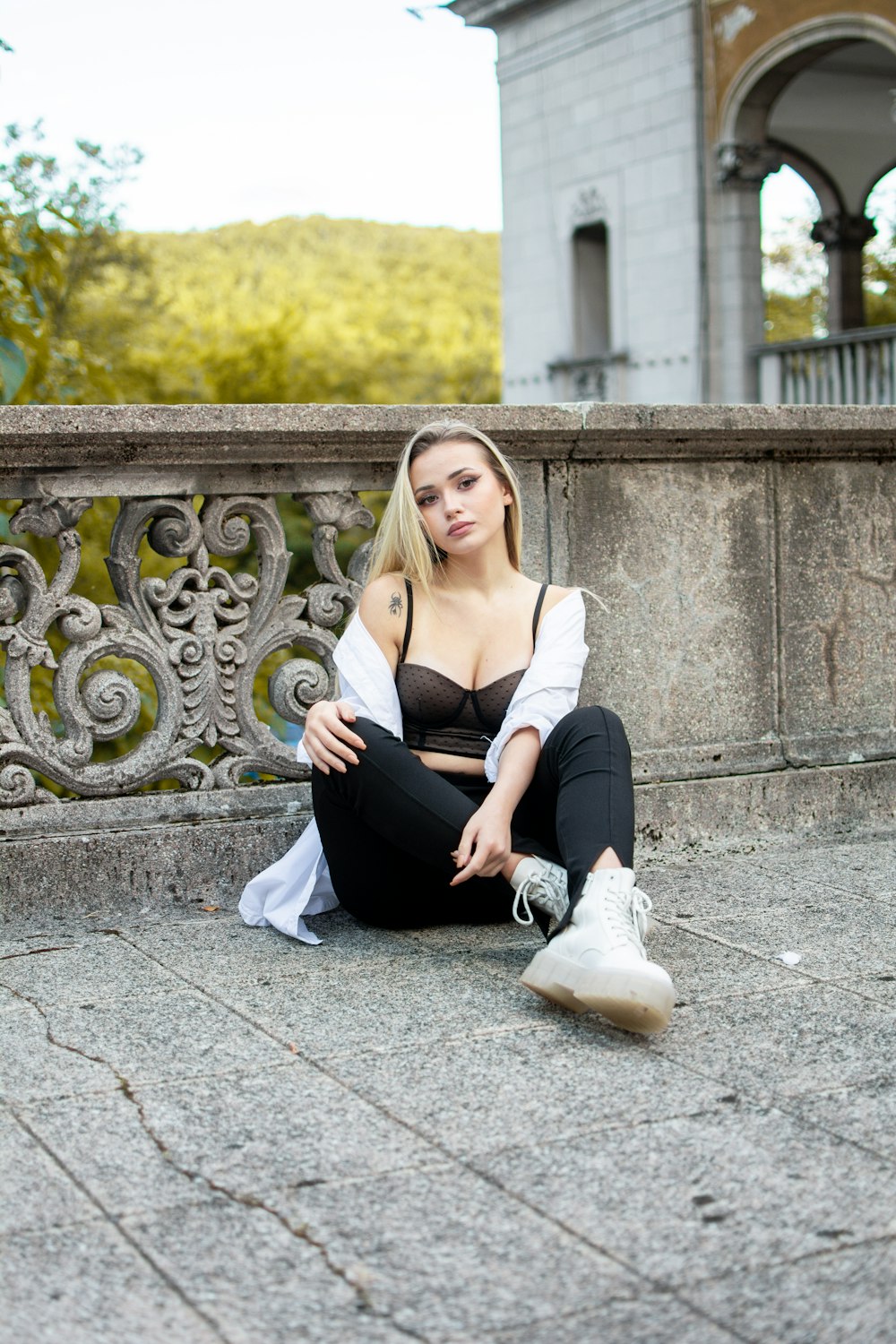 woman in gray long sleeve shirt and black pants sitting on gray concrete floor