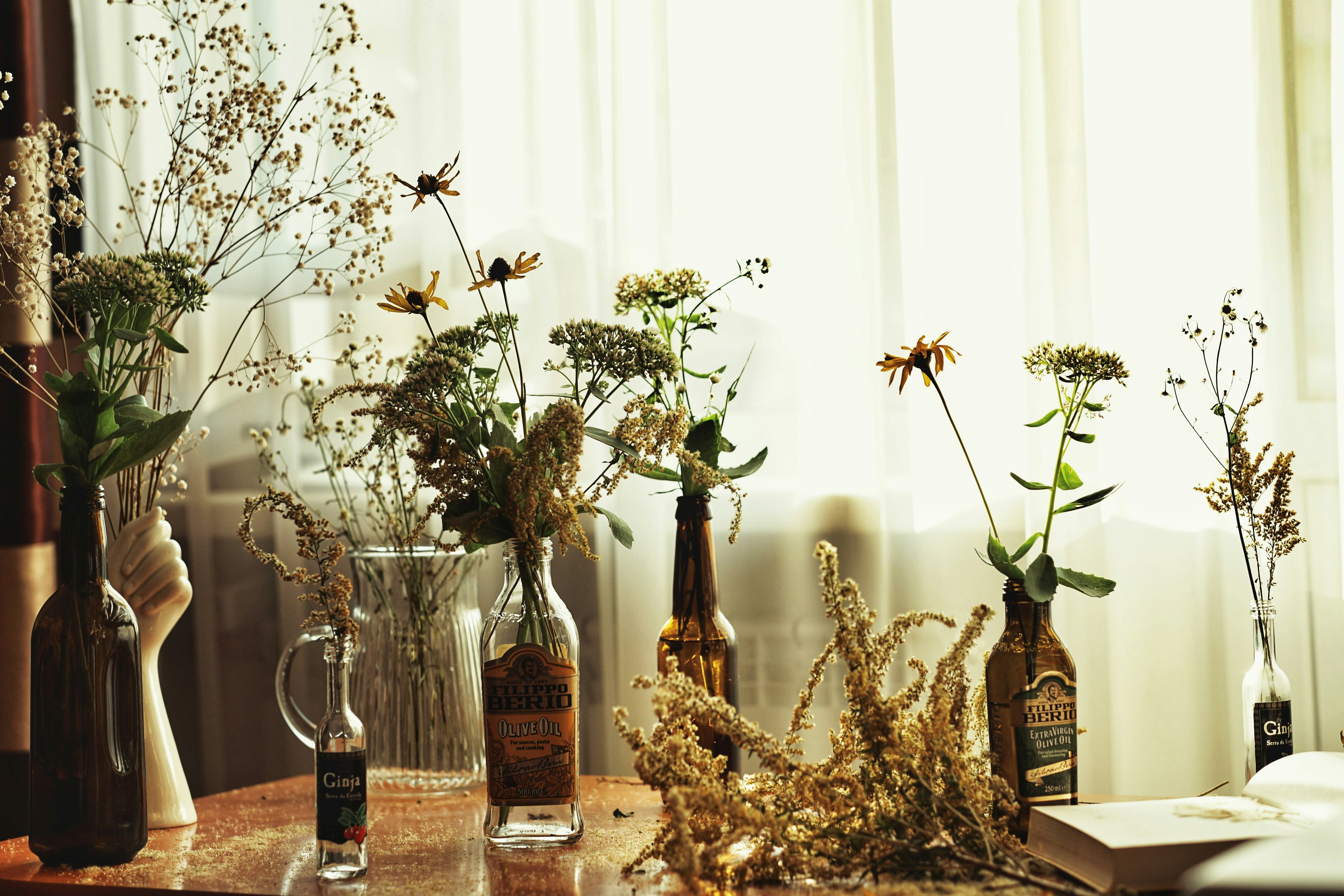clear glass bottle beside white flowers in clear glass vase