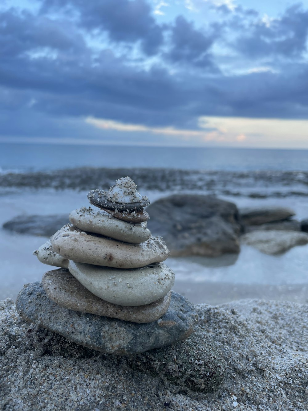 gray and brown stone on gray sand near body of water during daytime